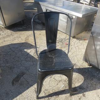 Black metal chair with curved backrest and simple design. Slight wear visible. Suitable for industrial or modern decor.
