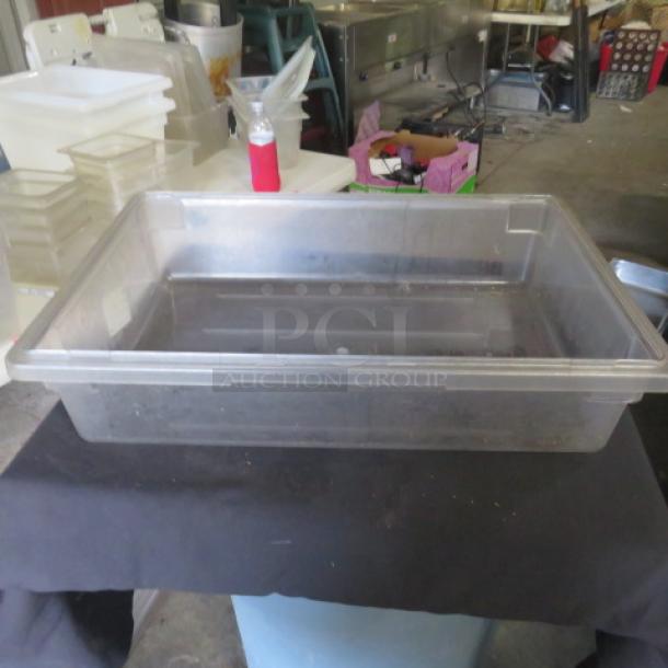 Cambro 8.75-gallon clear food storage container in used condition, showing minor scratches. Stacked on a table in a warehouse.