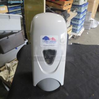 Wall mount soap dispenser, brand "Cleaner Solutions," model "Foam-O-Matic," new condition, sleek white design, visible label.