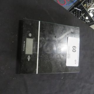 Digital kitchen scale with black surface and LCD display. Slight wear visible. Tag indicates item 60.