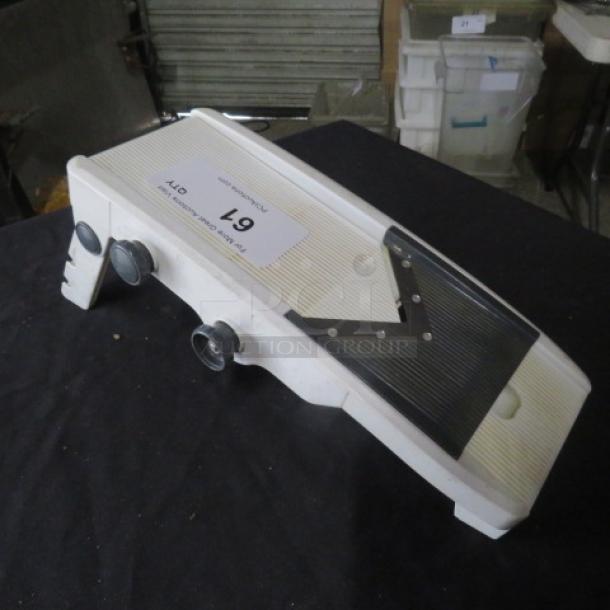 White mandolin slicer with adjustable thickness settings, stainless steel blades, and suction feet for stability. Model label "L9."