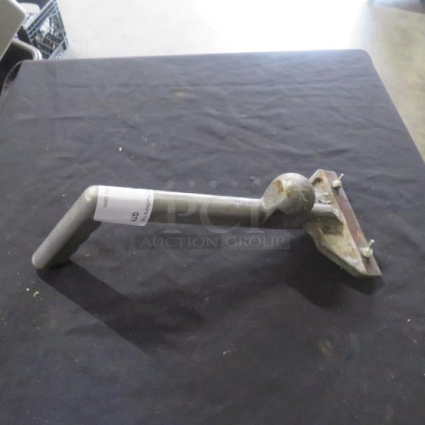 Metal griddle scraper with ergonomic handle and angled blade on display. Slight wear, auction tag visible on handle.