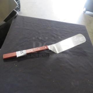 Metal hamburger turner with a wooden handle and three rivets, showing moderate wear. Auction tag labeled “65.”