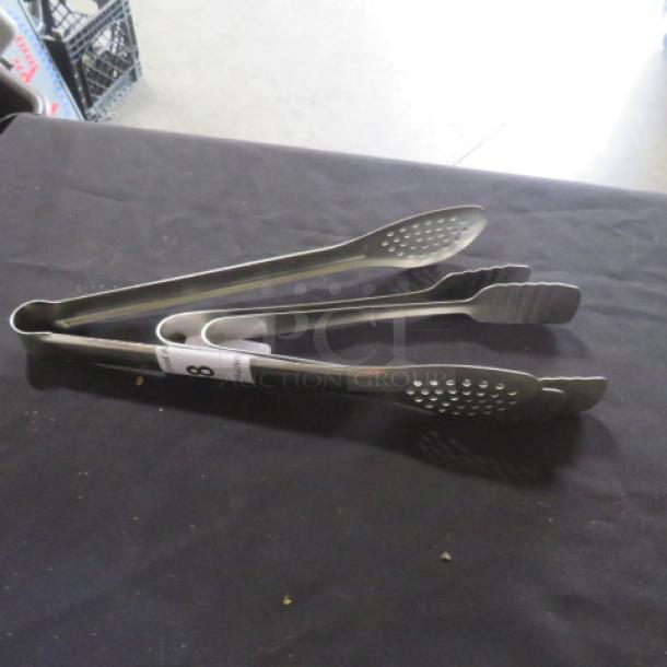 Assorted stainless steel tongs, set of three, in good condition, featuring perforated and scalloped tips for versatile use.