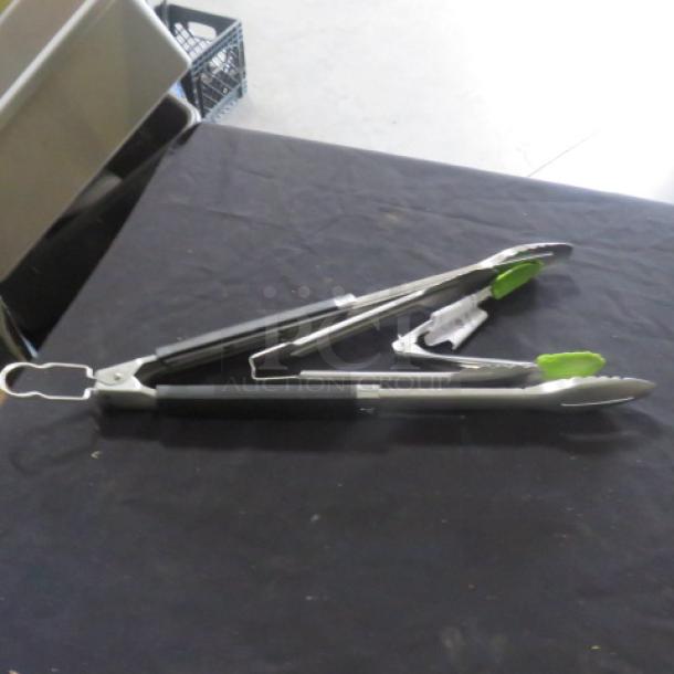 Assorted stainless steel tongs with green silicone tips and locking mechanism, in good condition, on black surface.