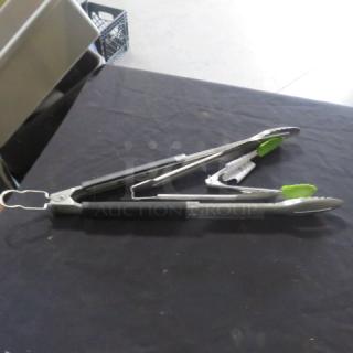Assorted stainless steel tongs with green silicone tips and locking mechanism, in good condition, on black surface.