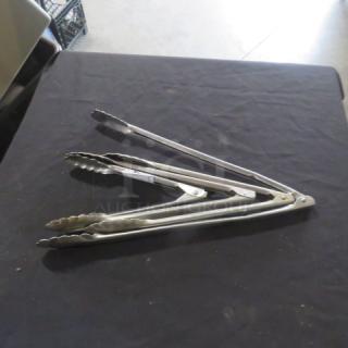 Assorted stainless steel tongs on table, scissor style, silver finish, slightly used condition, ideal for kitchen use.