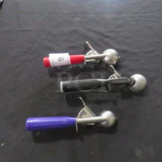 Three assorted dishers with red, black, and blue handles on black surface. Numbered tag "16" on red disher.