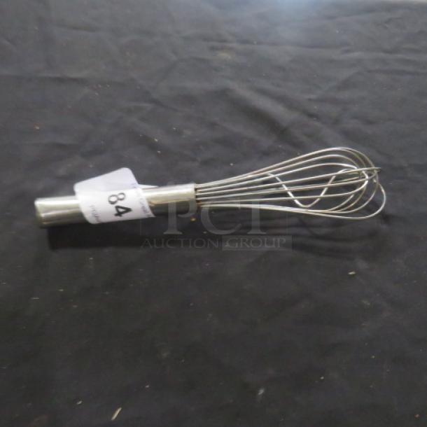 Stainless steel whisk with looped wire design and cylindrical handle, labeled with auction tag "84".