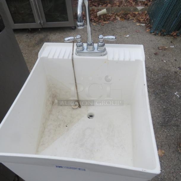 White utility sink with dual-handle chrome faucet, dimensions 19x24x44 inches. Some dirt present, ideal for garage use.