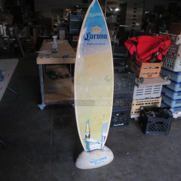 Corona surfboard display with Corona Extra logo, featuring a beach chair and bottle graphic, mounted on themed rock base.