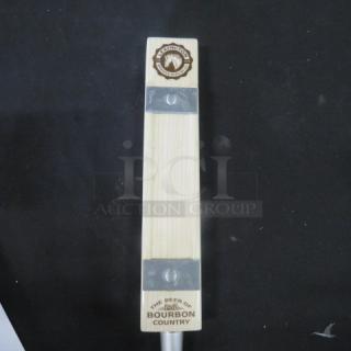 Wooden beer tap handle with "The Beer of Bourbon Country" label and engraved logo, metal accents, in good condition.