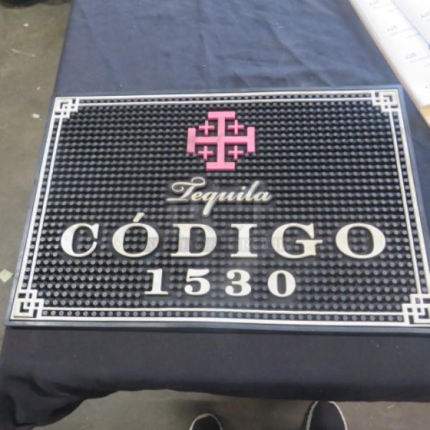 Código 1530 bar mat, 18x12 inches, black with pink and white logo, textured surface, used but in good condition.