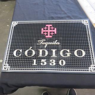 Código 1530 bar mat, 18x12 inches, black with pink and white logo, textured surface, used but in good condition.