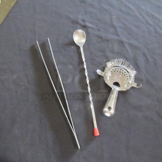 Assorted bar utensils including a twisted stirring spoon, metal tweezers, and a cocktail strainer with coil.