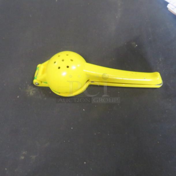 Yellow metal citrus juicer, hinged design, used condition, minor surface wear, ideal for lemons and limes.