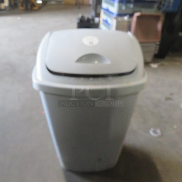 13.2-gallon trash can with swing top lid, light gray, used, sturdy plastic construction, suitable for home or office use.