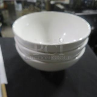 Three white ceramic bowls, each 8 inches in diameter, stacked on a table. Clean and in good condition.