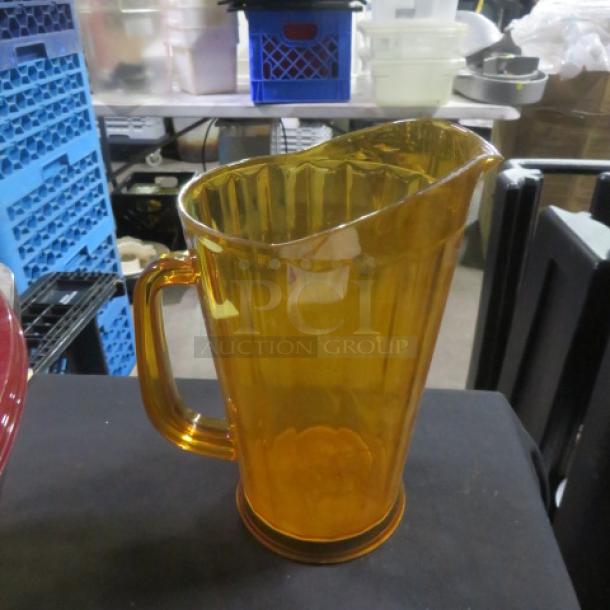 Amber polycarbonate pitcher with a handle, ribbed exterior design, used condition, suitable for beverages.