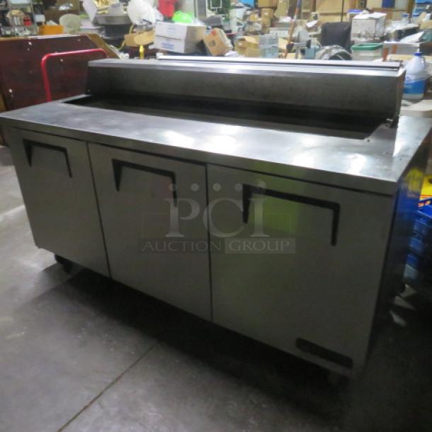 True TSSU-72-18 refrigerated prep table on casters; 3 doors; lid missing; 72.5x30x44 inches; 115V; working condition.