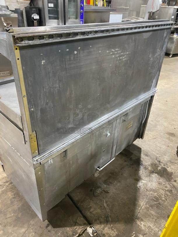 Wolf commercial stainless steel range, back view. Features natural gas, 6 burners, flat griddle, double oven, broiler, and salamander shelf. Minimal wear.