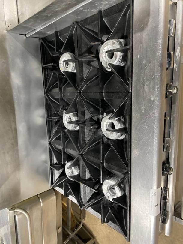 Wolf commercial stainless steel 6-burner gas range with raised flat-griddle, double oven, broiler, and salamander shelf.