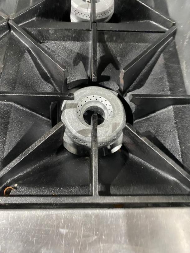 Wolf commercial stainless steel 6-burner gas range with a raised flat-griddle top, shown is one burner in detail.