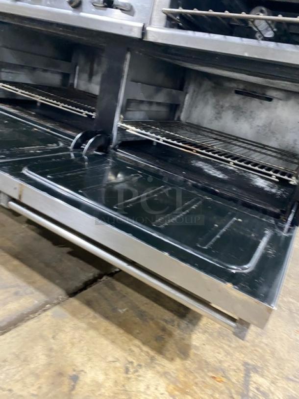 Wolf commercial stainless steel double oven with wired rack, open doors, and visible interior. Gas-powered, includes salamander shelf.