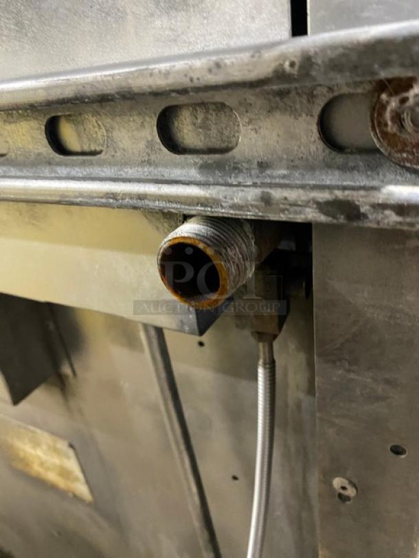 Rusty metal pipe connection on a commercial appliance, showing wear. Part of Wolf's stainless steel range.