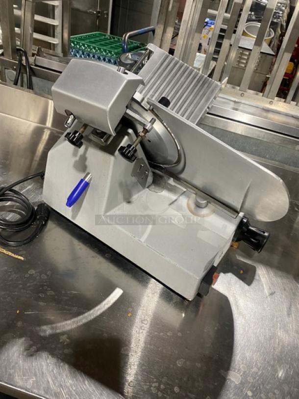 Commercial electric countertop deli meat slicer, metal body, sharp circular blade, used condition, power cord attached.