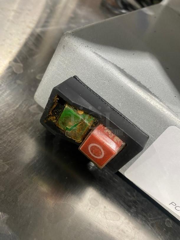 Commercial electric deli meat slicer, countertop model, visible wear, power switch with green and red buttons.