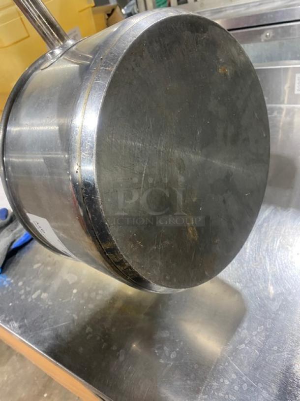 Stainless steel commercial round sauce pot, bottom view. Moderate wear with scuff marks. Ideal for restaurant use.