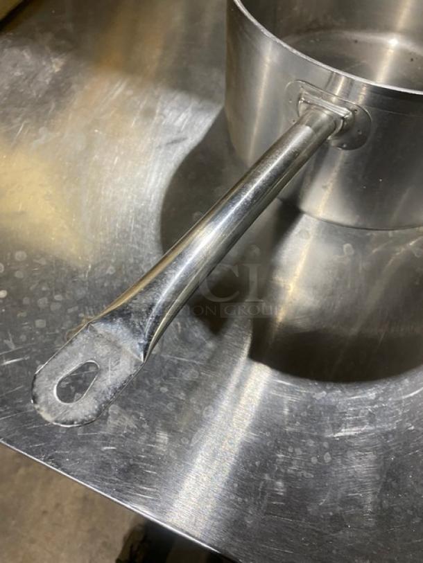 Commercial round sauce pot, stainless steel, long handle, used condition, sturdy build, ideal for professional kitchens.