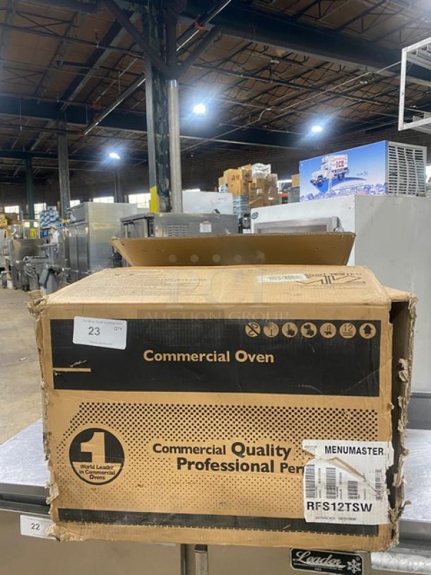 New Menumaster RFS12TSW countertop microwave oven in box; stainless steel, digital controls, 120V. Model and SN visible.