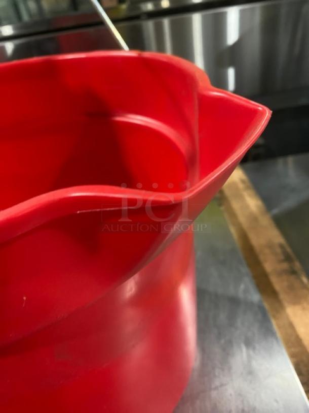 Red commercial round mop bucket with pale style handle, durable plastic, excellent condition, ideal for utility use.