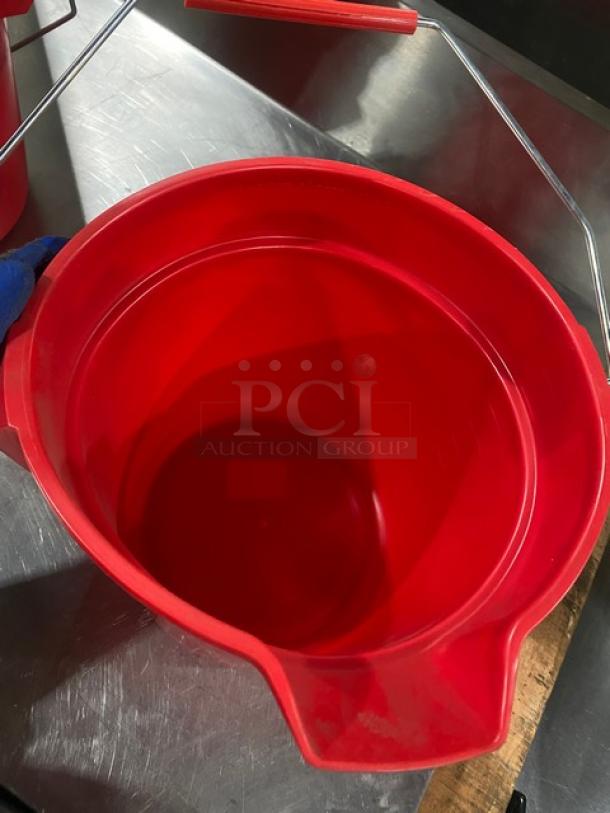 Red round commercial mop bucket with pale-style handle, used condition. Suitable for utility tasks.