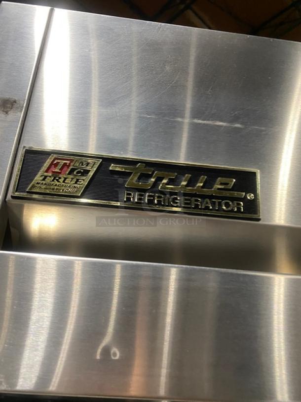 True TM52 commercial stainless steel 2-door reach-in refrigerator with poly-coated rack, on casters, badge visible.