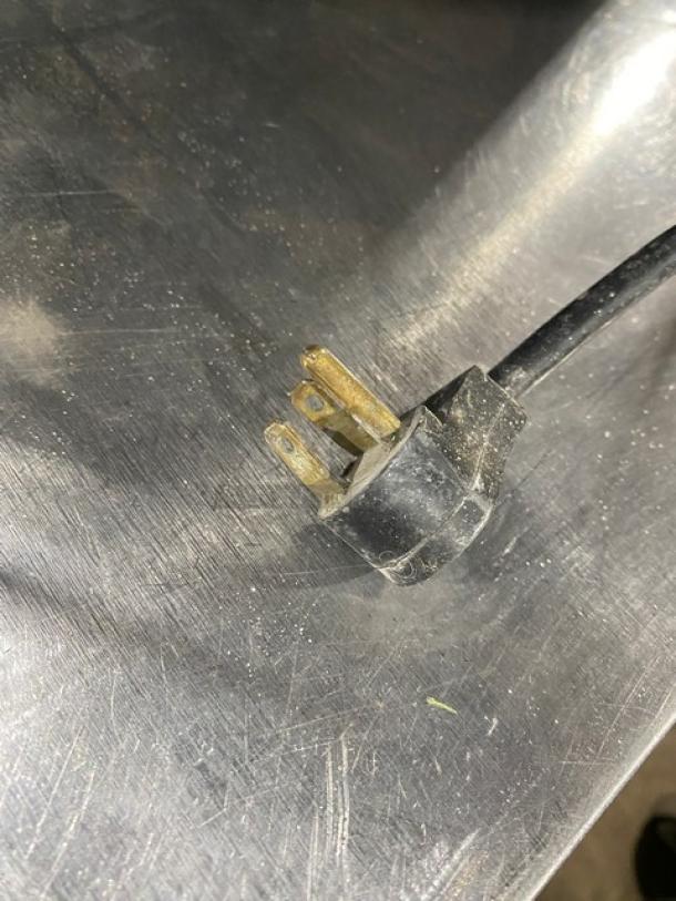 Close-up of a three-prong plug for the Delfield Enodis Series Model 402 commercial refrigerator, showing wear.