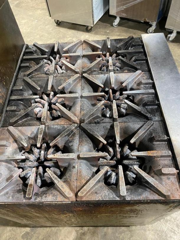 Garland stainless steel 6-burner gas range and oven combo, with back splash, overhead salamander shelf, and wired oven rack.