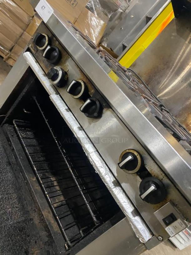Garland stainless steel gas-powered 6 burner range/oven combo with back splash, overhead salamander shelf, wired oven rack, and casters.