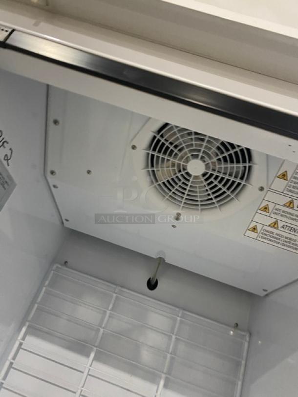Turbo Air TGIM23WN Ice Merchandiser Freezer with glass swing door, poly-coated wire rack, and warning labels visible.