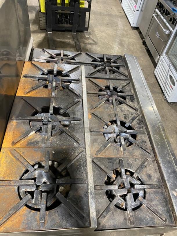 Jade Range stainless steel 8-burner commercial stove, natural gas, with chef base, backsplash, double back guard, and flue riser. Visible wear.