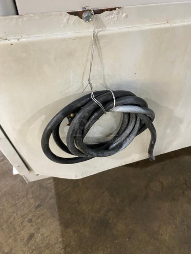 Hussmann commercial freezer, model LBN8, with signs of wear, displaying a coiled power cord attached to its exterior.