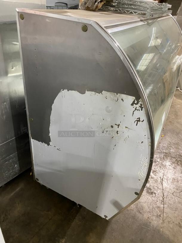 Leader Commercial 96" stainless steel refrigerated display case, model NRHD96. Features curved glass, rear sliding doors, and storage compartment. Visible wear on exterior.