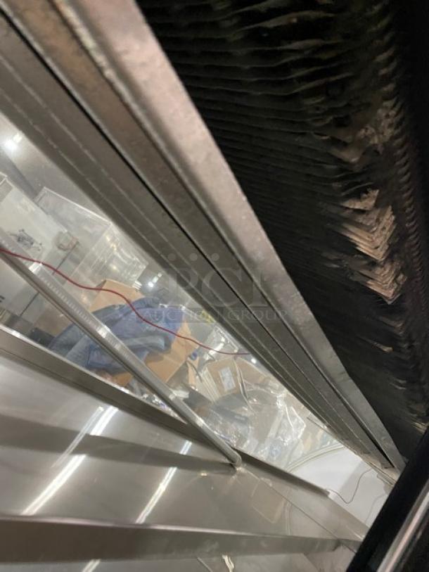 Leader stainless steel refrigerated display case, Model NRHD96, with curved glass front. Features rear glass sliding doors and lower storage.