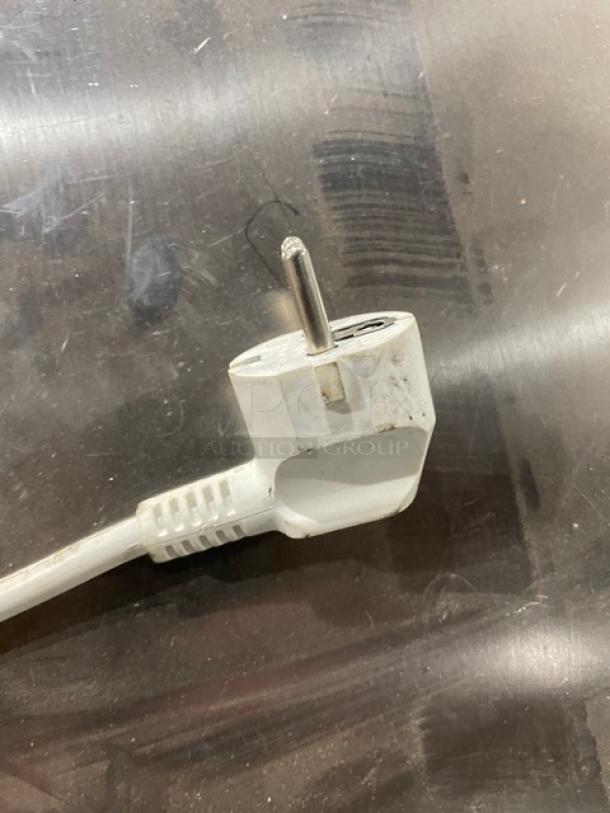 White power plug in fair condition on a metallic surface.