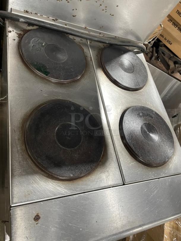 Imperial commercial stainless steel electric hot plate range with 4 burners, overhead salamander shelf, and wire oven rack.