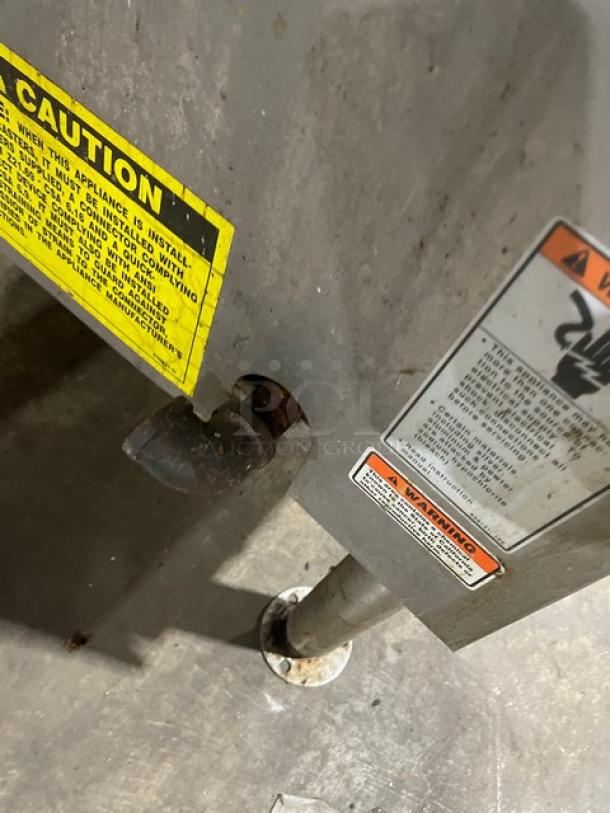 Vulcan commercial stainless steel tilt skillet, natural gas, with safety warnings visible, mounted on legs.