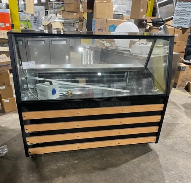 Commercial black slanted glass refrigerated bakery/deli merchandiser display case with rear prep area, storage, and sliding doors, on casters.