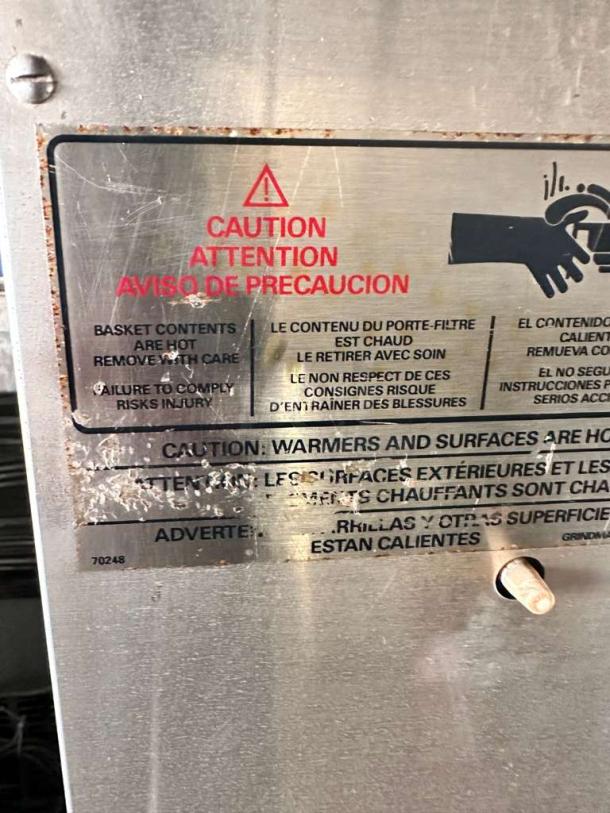 Safety warning label on Mazzer Robur Electronic Coffee Grinder. Indicates hot surfaces. Model 70248 visible.